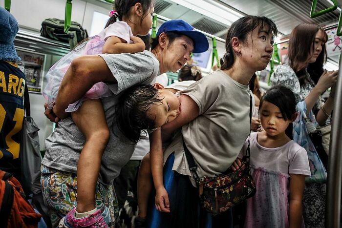 Crowded streetcar scene showing candid street moments of tired children and adults capturing humanity and tender interactions.