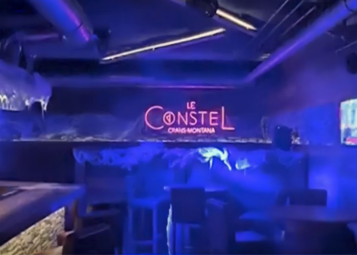 Interior of a dimly lit Swiss bar with neon signs where a waitress escaped a tragic fire incident.