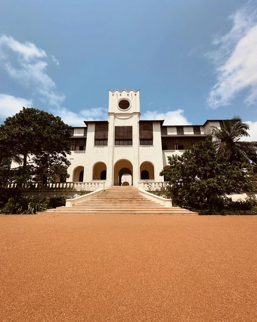 Colonial-style building with wide stairs surrounded by greenery under a blue sky representing paid leave in global nations.