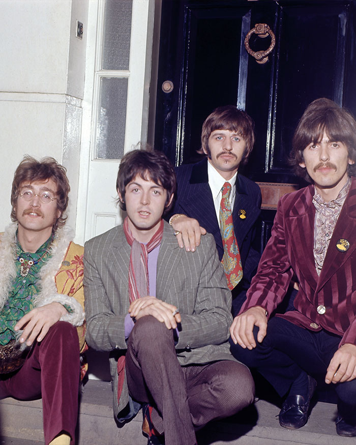 The Beatles sitting on steps outside a door, representing hidden stories in famous songs and music history.
