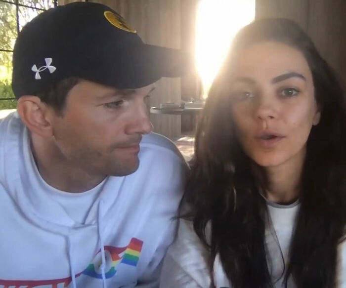 Ashton Kutcher with a rough look sitting next to Mila Kunis in casual clothes, natural lighting indoors