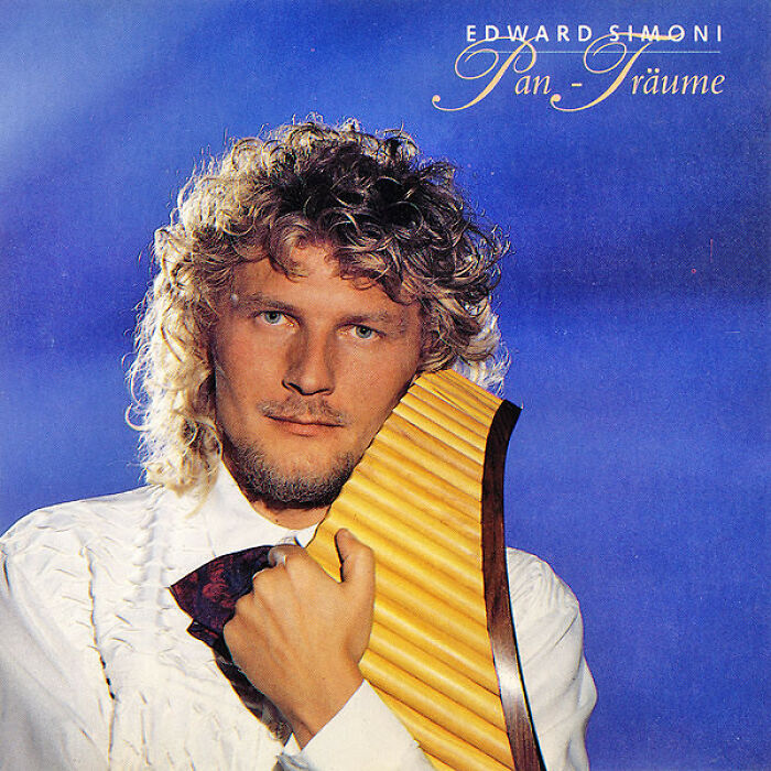 Man with curly hair holding a pan flute against a blue background on a hilariously bad album cover.