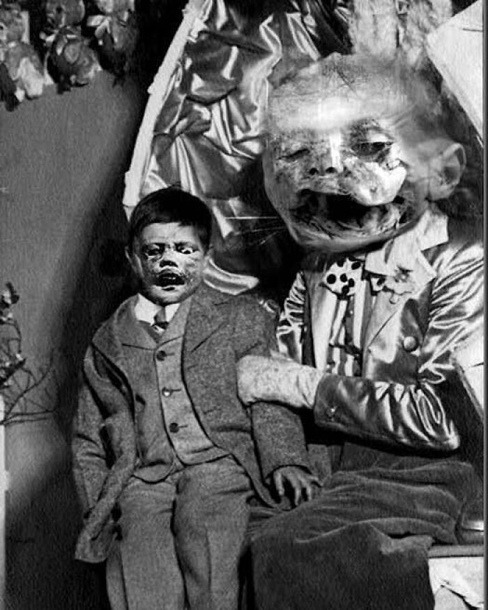 Old black and white creepy photo showing distorted faces on a child and an adult in vintage clothing.