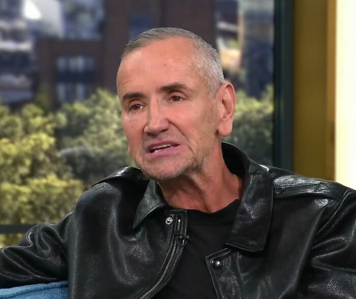 Man in a black leather jacket speaking during an interview, addressing DJ at Brooklyn Beckham's wedding dance accusations.