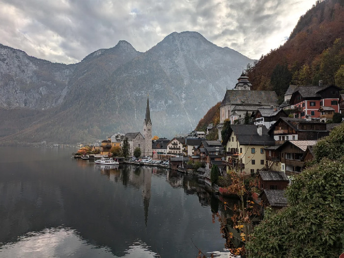 Scenic view of one of the best countries to raise a family with mountains, water, and traditional village buildings.