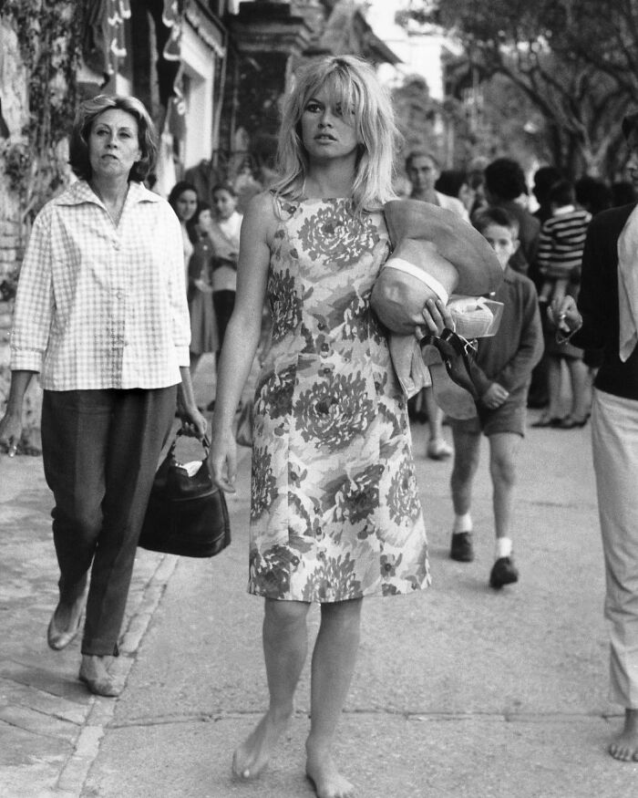 Young woman barefoot walking on street holding shoes and hat, a powerful photograph reflecting history of humanity.