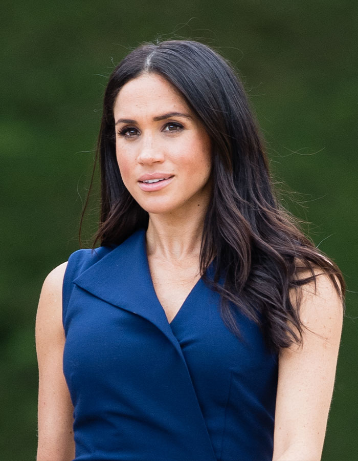Meghan Markle in a sleeveless blue dress posing outdoors, part of viral Meghan Markle evil stare compilation content.