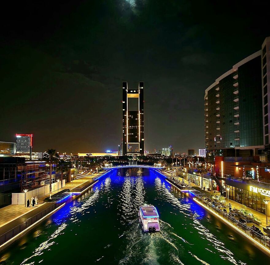 Nighttime cityscape with illuminated buildings and a boat on water, highlighting nations setting new global paid leave standards.