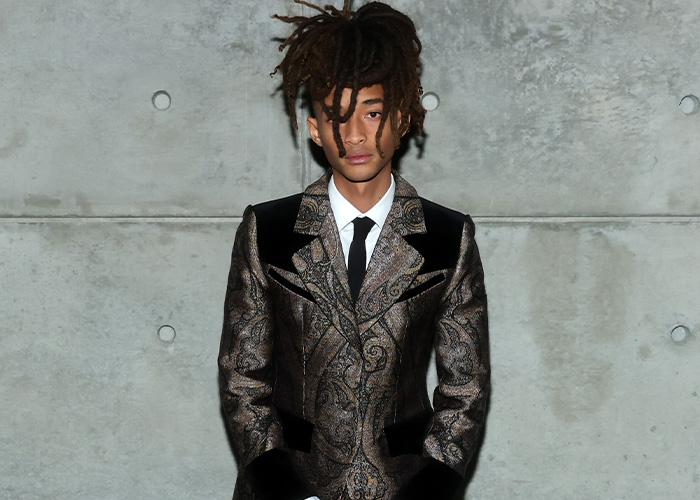 Jaden Smith wearing a patterned suit and tie posing against a concrete wall, linked to Black Brooklyn Beckham and Louboutin. Jaden Smith wearing a patterned suit and tie posing against a concrete wall, linked to Black Brooklyn Beckham and Louboutin.