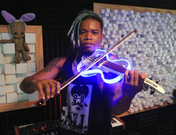 Musician playing a glowing electric violin in a studio setting, related to Will Smith accused of harassing and grooming.
