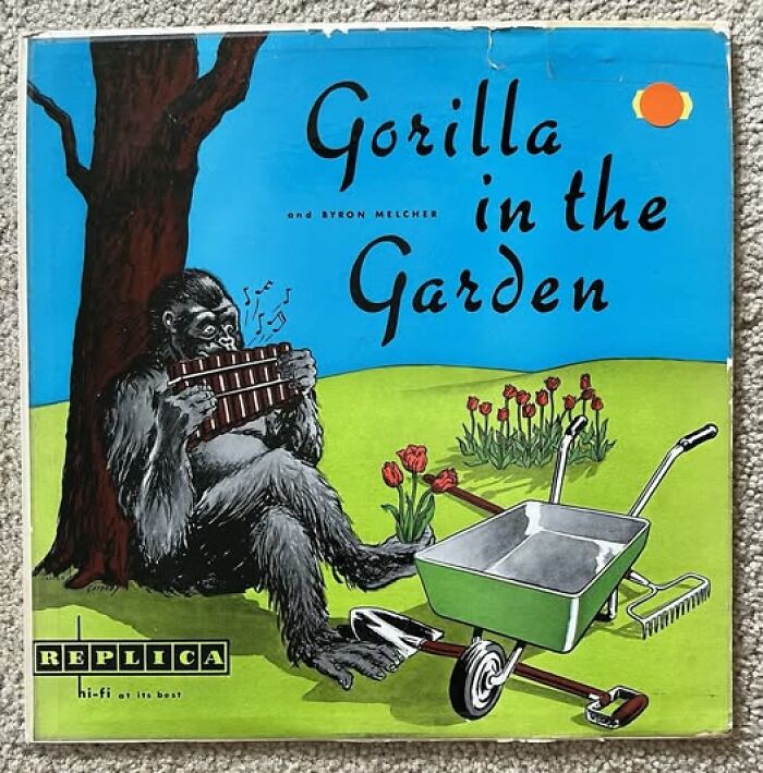 Gorilla playing pan flute sitting by tree with garden tools on humorous, bad album cover illustration.