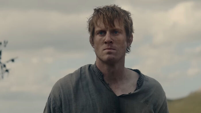 A Knight of the Seven Kingdoms character with messy hair and worn clothing standing outdoors under a cloudy sky. A Knight of the Seven Kingdoms character with messy hair and worn clothing standing outdoors under a cloudy sky.