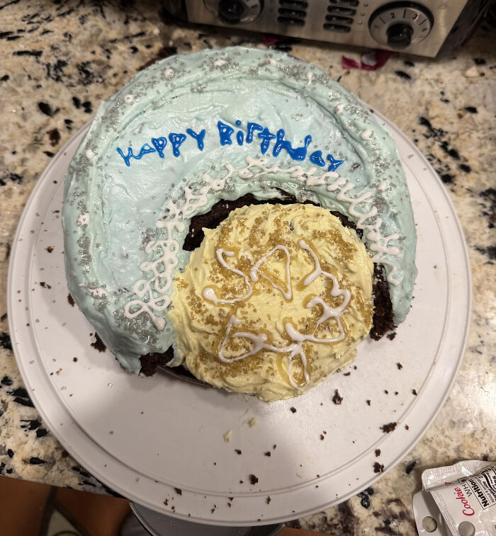 Partially broken birthday cake with messy frosting and uneven decoration, an example of ruined dessert.
