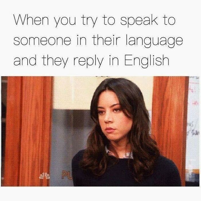 Young woman looking disappointed with text about speaking another language and replying in English, travel memes humor.