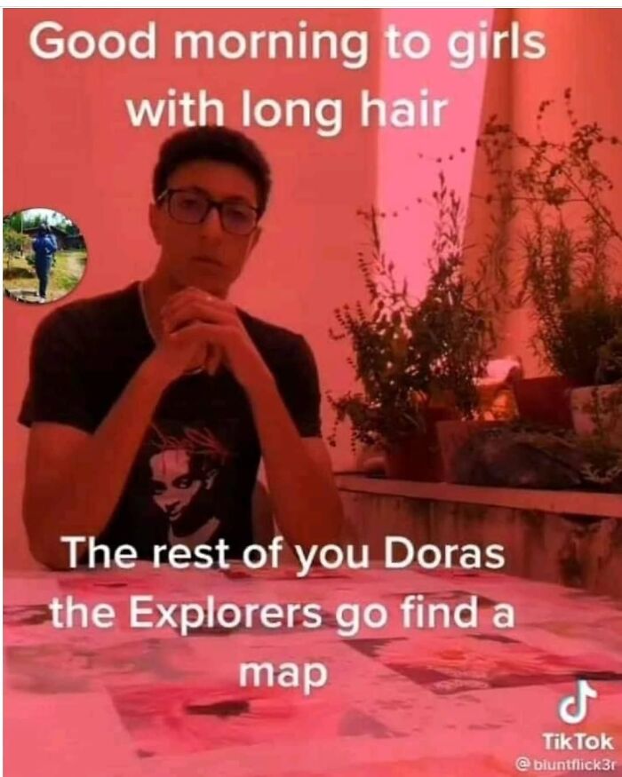 Young man in glasses sitting at a table with meme text, humorous content with a touch of darkness in a pink-lit room.