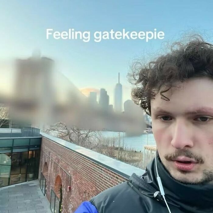 Man taking a funny screenshot selfie outdoors with blurred city skyline and text feeling gatekeepie visible.