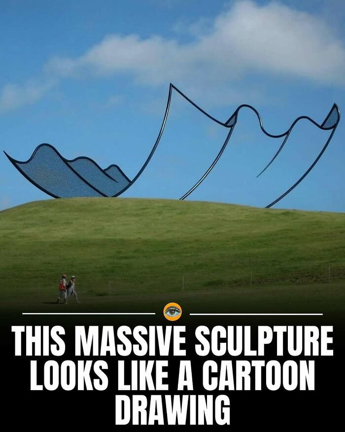 Massive outdoor sculpture resembling a cartoon drawing with lighthearted facts and pics in a green field under blue sky.