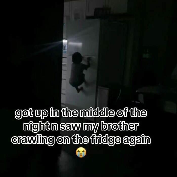 Child crawling on the fridge at night, one of the funniest screenshots people took showing a humorous moment in a dark kitchen.