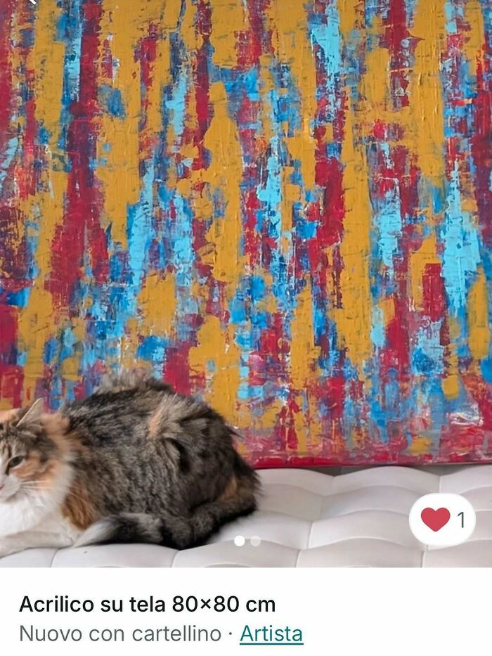 Cat resting on a white surface with colorful abstract painting in the background, highlighting cats in Vinted ads.