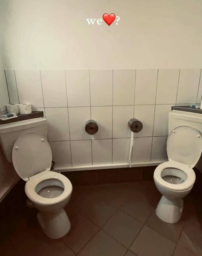 Two adjacent toilets in a tiled bathroom with the text we heart above, capturing random and bizarre memes humor.