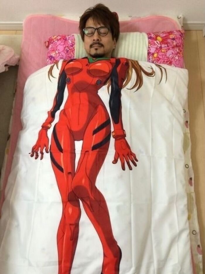 Man lying in bed covered with a blanket featuring a bizarre anime character, showcasing random and bizarre memes humor.