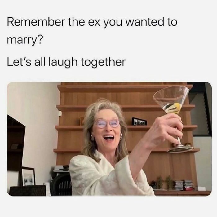 Woman raising a glass and laughing with a meme about exes to provide funny memes distraction.