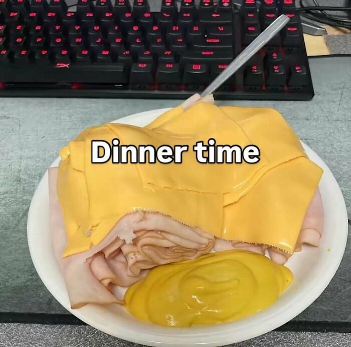 Plate with sliced turkey, cheese slices, and mustard on a desk, illustrating random and bizarre memes humor.