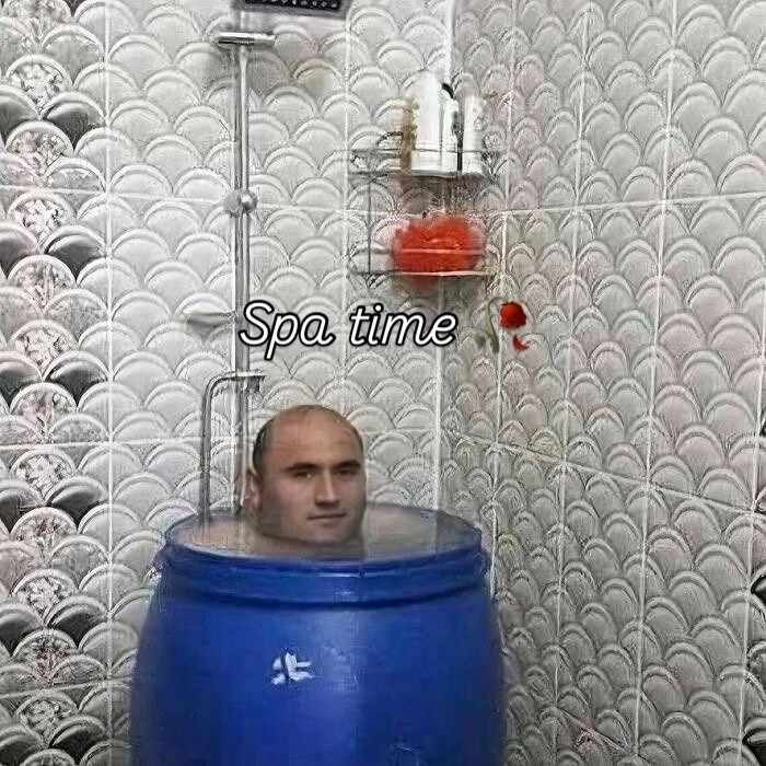 Man soaking in a blue barrel under a showerhead with wall shelves, a bizarre meme from random and bizarre memes collection.