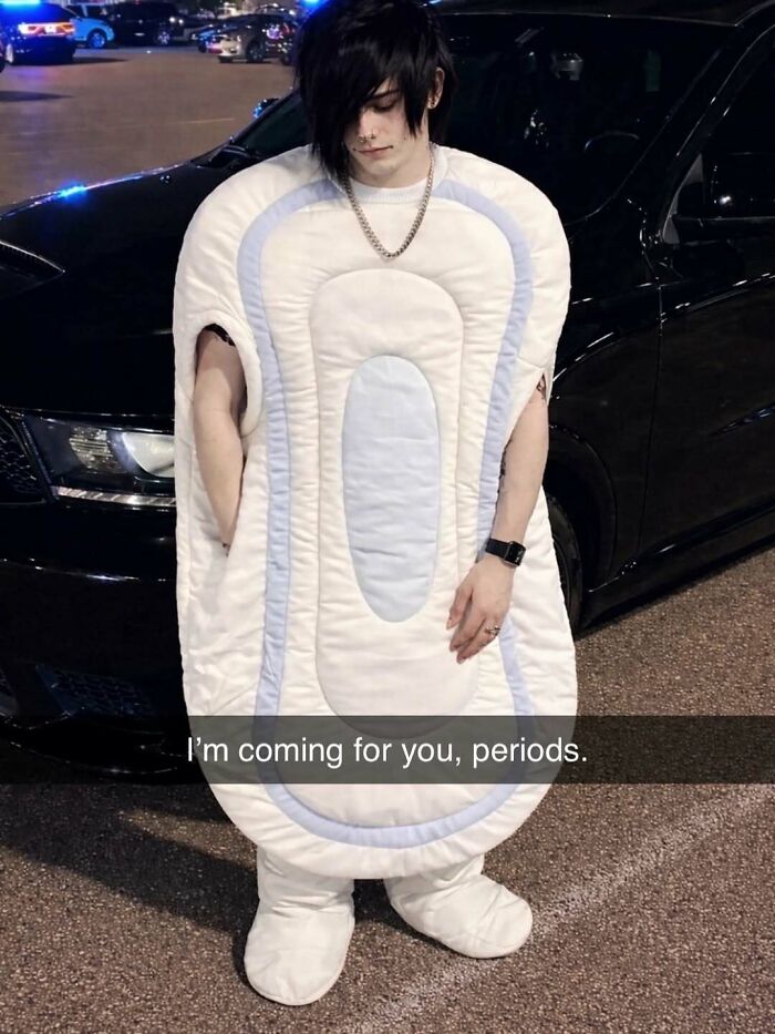 Person in bizarre menstrual pad costume standing outside a parked car with caption about periods in a random meme.