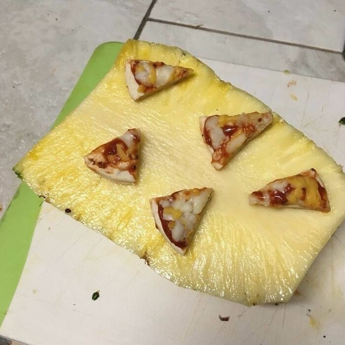 Slice of pineapple with small pizza slices placed on top, showcasing a random and bizarre meme concept.
