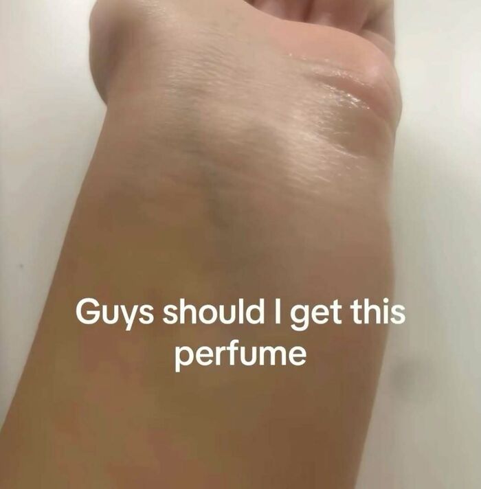 Close-up of a wrist with a faint mark and humorous text asking if they should get this perfume, a random bizarre meme.