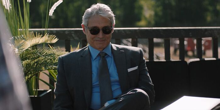 Man wearing sunglasses and a dark suit sitting outdoors, related to The Pitt Season 2 guest star episode 3.