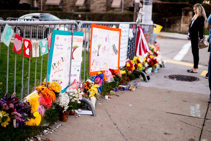 Memorial flowers and drawings along a street fence, reflecting the tragic true story behind Tree Of Life reference.