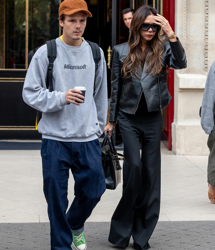 Cruz Beckham walking with Victoria Beckham outside, both dressed casually, related to Brooklyn wedding dance claim.