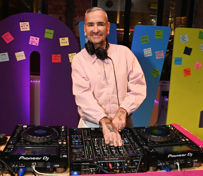 DJ at Brooklyn Beckham's wedding adjusting controls on Pioneer DJ equipment with colorful notes in the background.