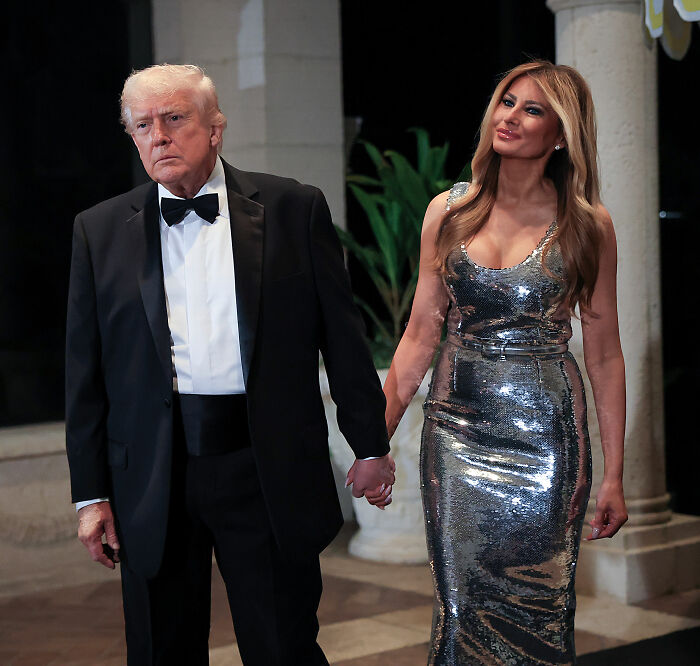 Melania Trump and Donald Trump holding hands at Mar-a-Lago, showcasing Melania Trump's body language during New Year's Eve event.