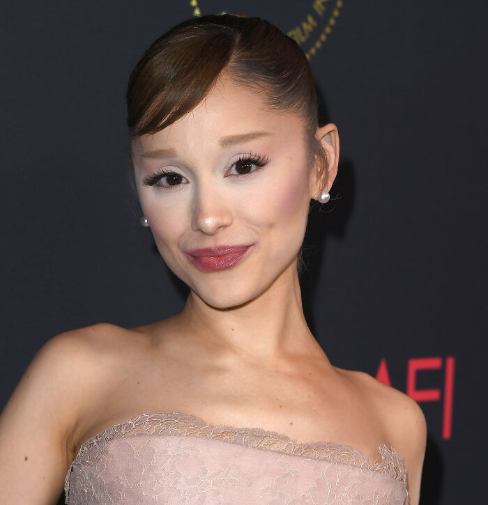 Ariana Grande posing at an event, showcasing unusual and bizarre mannerisms sparking numerous fan theories.