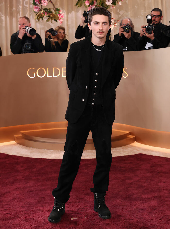 Timoth&eacute;e Chalamet on the red carpet at the Golden Globes event, dressed in black with photographers in the background.