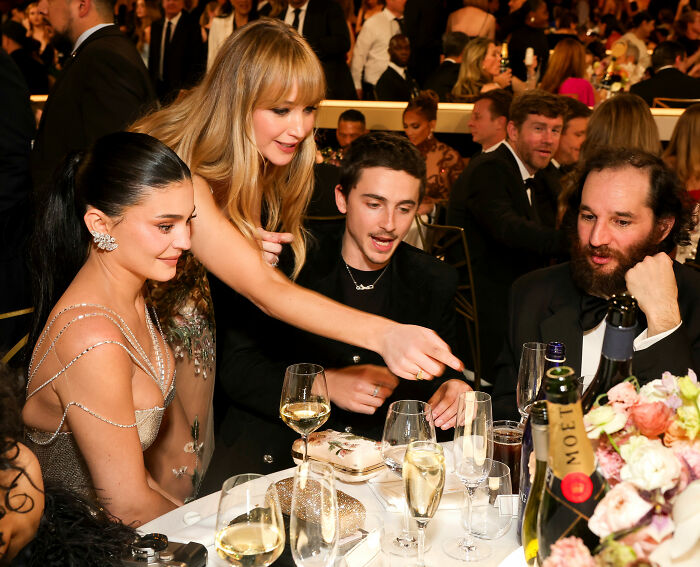 Celebrities enjoying Golden Globes food at a formal event, with drinks and elegant table settings visible. Celebrities enjoying Golden Globes food at a formal event, with drinks and elegant table settings visible.