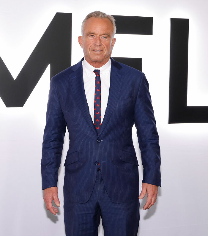 Man in a blue pinstripe suit and patterned tie posing at an event featuring worst MAGA looks from documentary premiere.