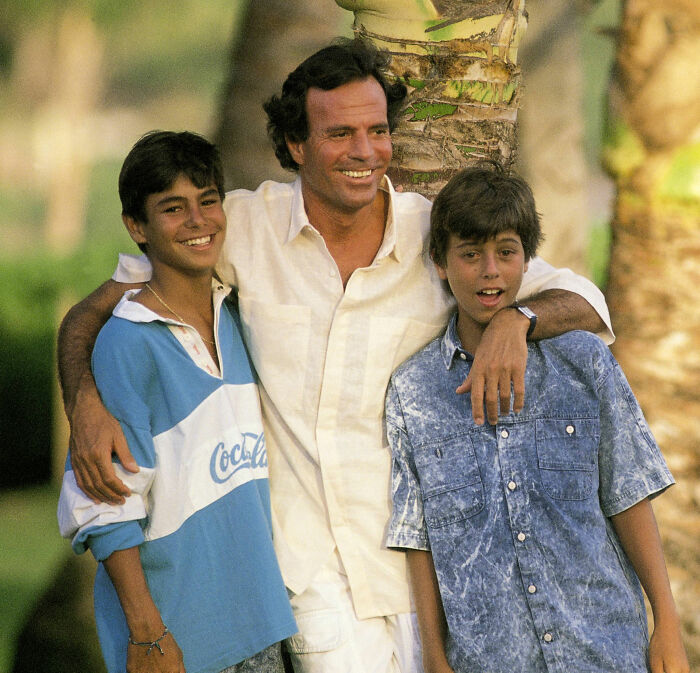 Julio Iglesias with his two sons outdoors, Enrique Iglesias' famous father under investigation amid accusations.