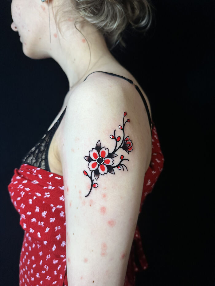 Floral tattoo on upper arm with red and black ink, showcasing cool tattoos that look so real and artistic on fair skin.