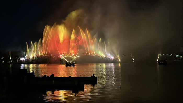Nighttime water fountain show in Central Florida reflecting vibrant colors over calm water, showcasing beauty and silence.