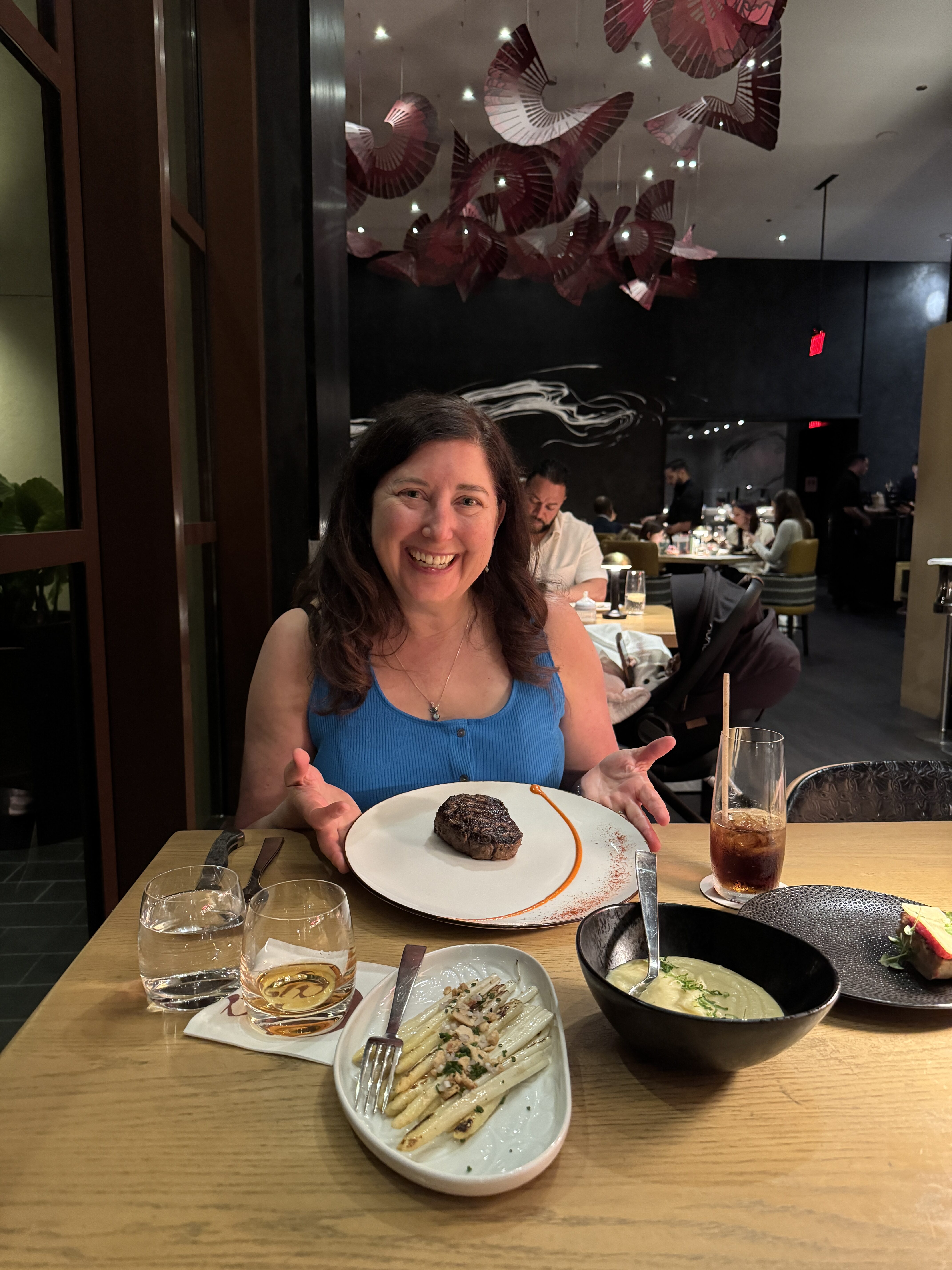 Woman smiling in a Central Florida restaurant enjoying a steak dinner, showcasing silence, beauty, and real emotion in dining.