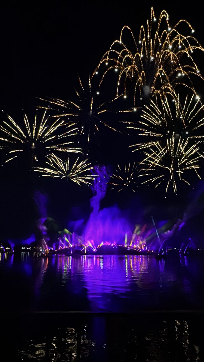 Fireworks and colorful light show over calm water, capturing the beauty and real emotion of Central Florida at night.