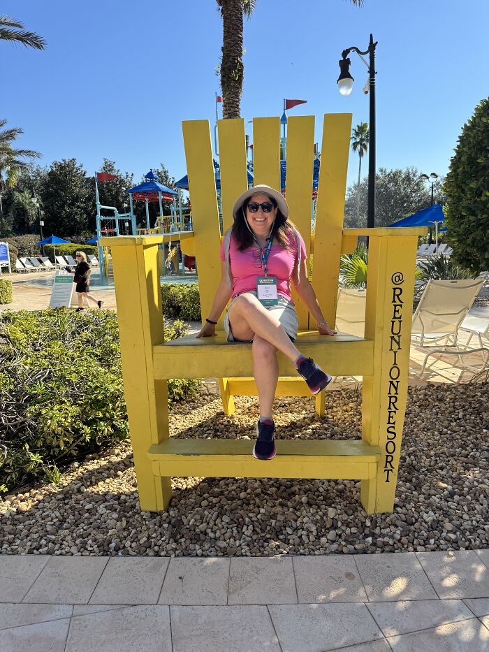 Woman sitting on oversized yellow chair at Reunion Resort in Central Florida, enjoying beauty and calm atmosphere.
