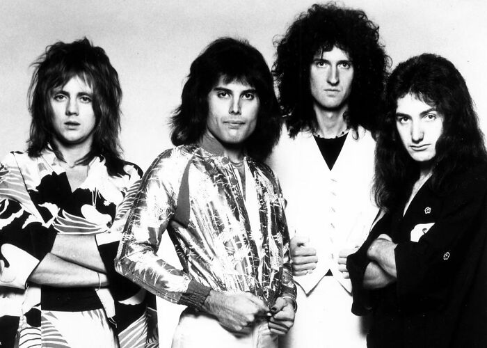 Four members of the band Queen posing for a black and white photo, highlighting Freddie Mercury's secret daughter news.
