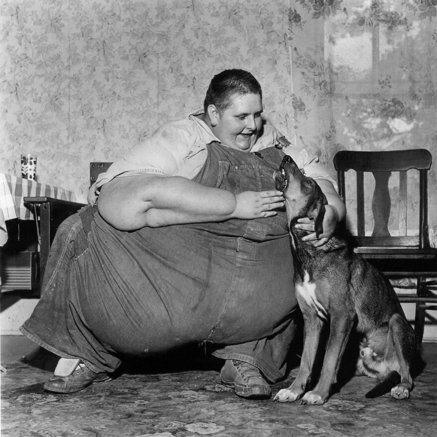 Heaviest recorded person in history Robert Earl Hughes sitting on the floor, smiling and petting a large dog indoors.