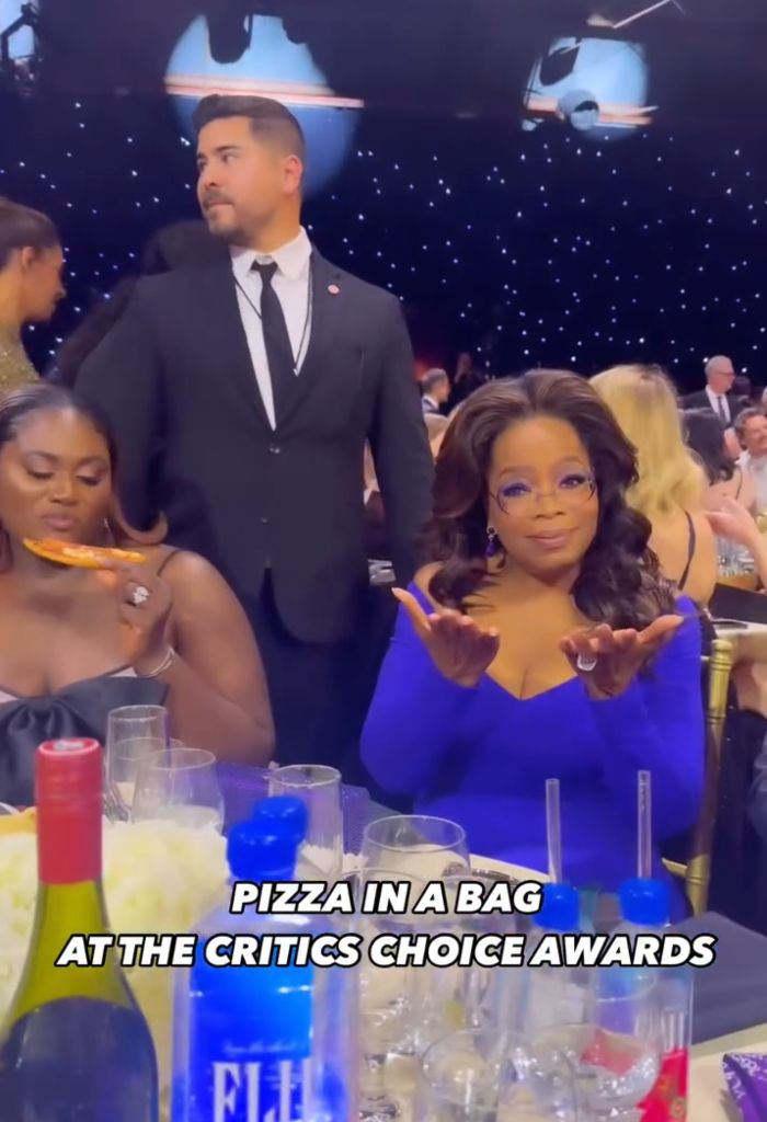 Oprah Winfrey and guests at the Critics Choice Awards, highlighting disappointing food with pizza in a bag on the table.