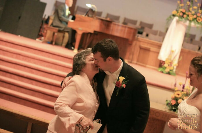 Groom awkwardly kissing an older woman in a church setting, capturing a funny awkward wedding photo moment.